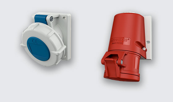 weiß-blaue Anbausteckdose mit Schraubdeckel und rote Wandsteckdose mit Klappdeckel