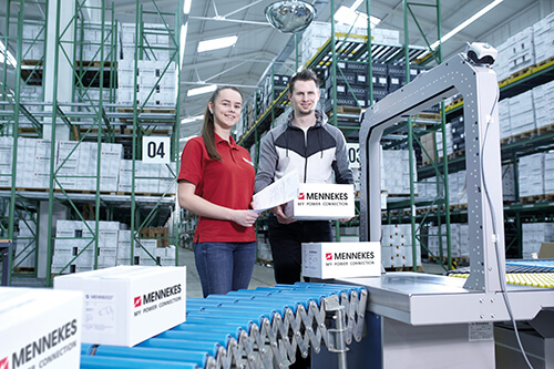 Zwei Personen stehen hinter einem Fließband voller Kartons