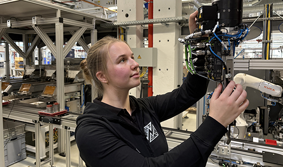 Auszubildende zur Elektronikerin für Betriebstechnik montiert eine industrielle Steuerungseinheit in der Fertigung.