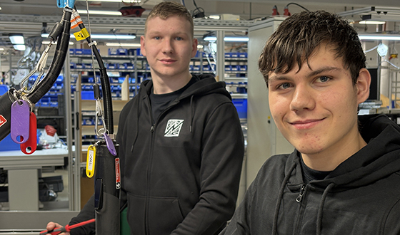 Zwei Auszubildende im Bereich Industrieelektrik arbeiten an elektrischen Komponenten in der Fertigung.