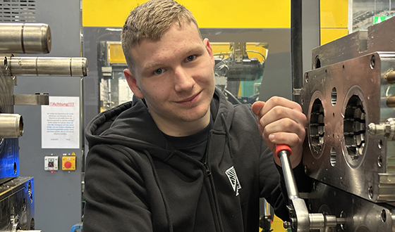 Auszubildender im Bereich Kunststoff- und Kautschuktechnik führt Wartungsarbeiten an einer Produktionsmaschine durch.