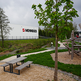 Weißes MENNEKES Produktionsgebäude hinter einem grünbebauten Park