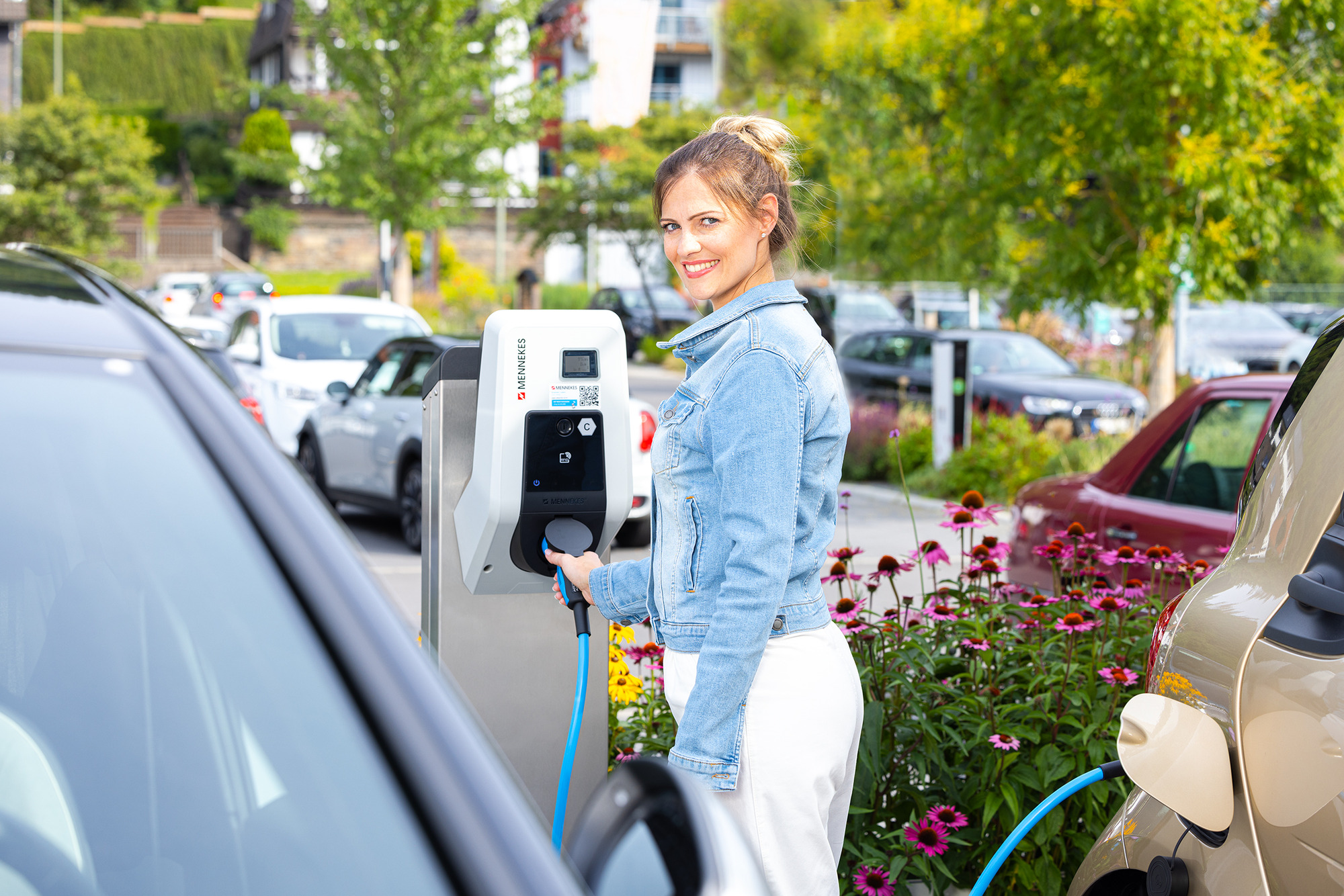 Kundin lädt ihr E-Auto auf Kundenparkplatz während des Einkaufens