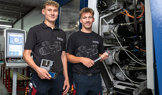 Industriemechaniker Zwei Auszubildende zum Industriemechaniker stehen an einer CNC-Maschine und bereiten Wartungsarbeiten vor.