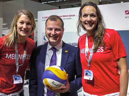 Drei Personen posieren mit einem Volleyball