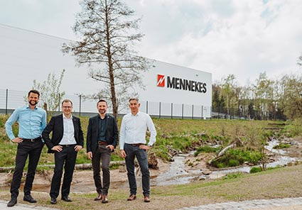 Eine Aufnahme von vier Männern mit der MENNEKES Produktionshalle im Hintergrund