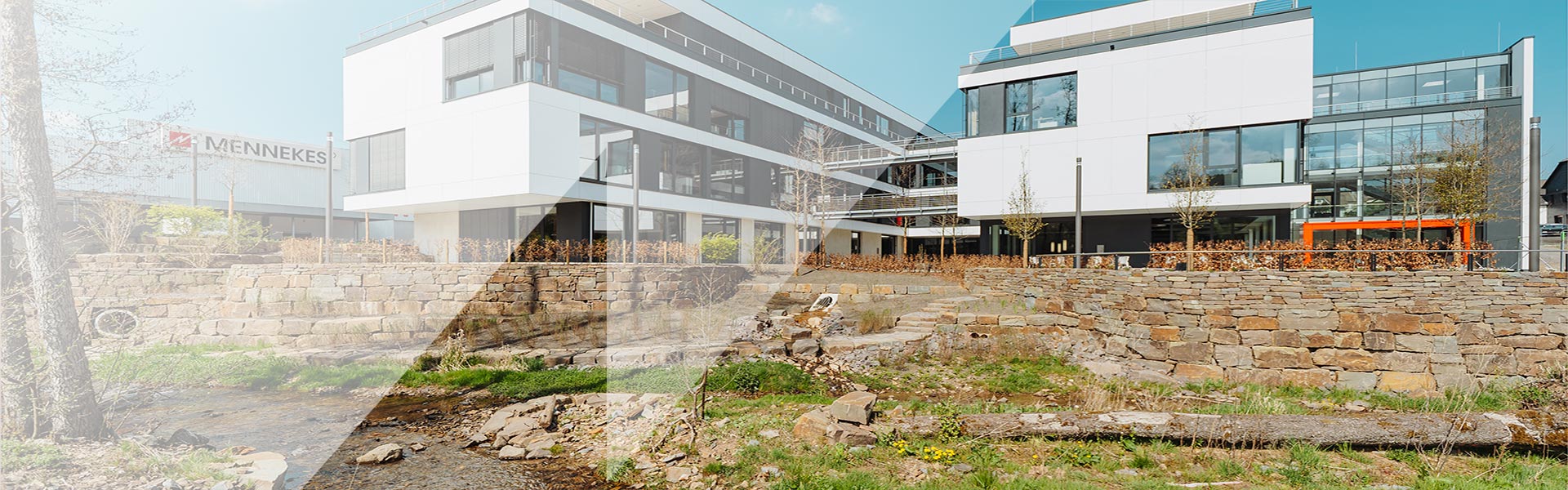Eine Aufnahme eines Bachlaufs mit den MENNEKES Verwaltungsgebäuden im Hintergrund