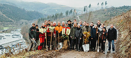 Eine Gruppe von Menschen mit Gartenwerkzeugen stehen am verregneten Waldweg