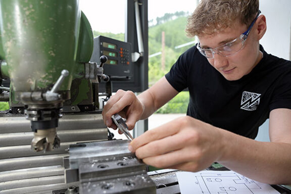 Industriemechaniker in Ausbildung arbeitet an einer Maschine