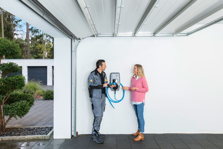 Installateur berät eine Kundin zur Handhabung einer Wallbox