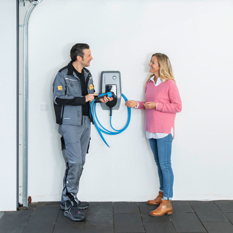 Installateur berät eine Kundin zur Handhabung einer Wallbox
