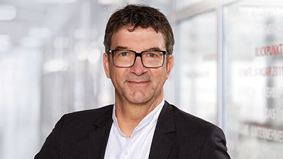 Portraitaufnahme einer männlichen Person mit Brille im Anzug