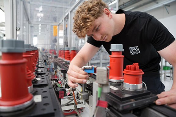 Ein Azubi zum Mechatroniker arbeitet an einer Maschine für Industriesteckvorrichtungen