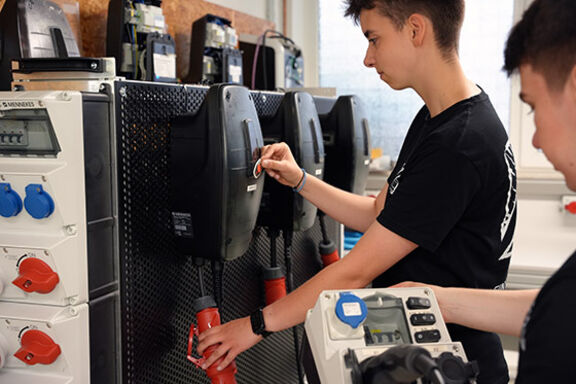 2 Auszubildende zum Elektroniker für Betriebstechnik bei Mennekes prüfen eine Wallbox