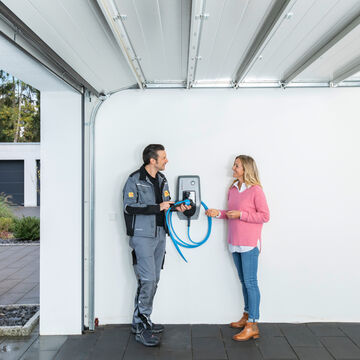 Installateur berät eine Kundin zur Handhabung einer Wallbox