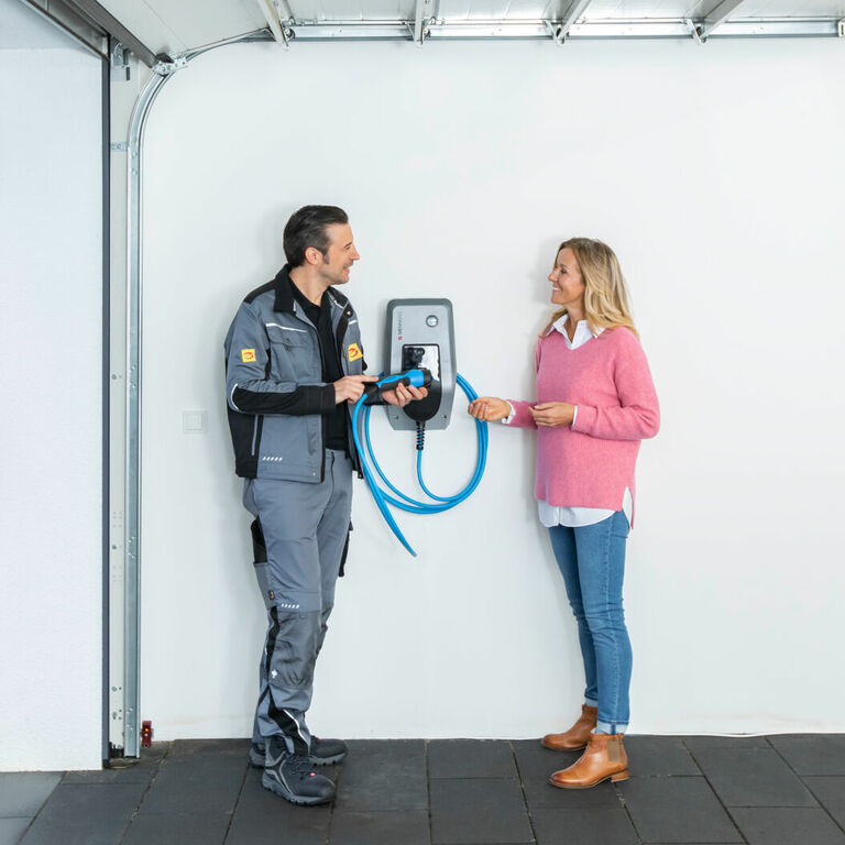 Installateur berät eine Kundin zur Handhabung einer Wallbox