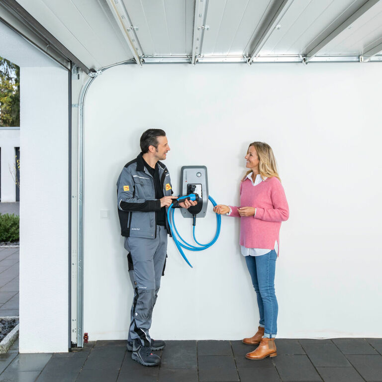 Installateur berät eine Kundin zur Handhabung einer Wallbox