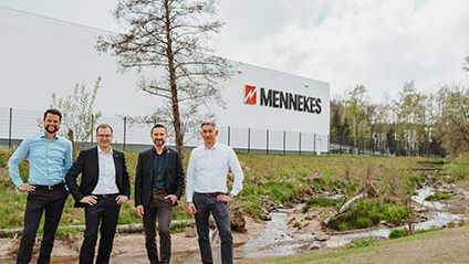 Eine Aufnahme von vier Männern mit der MENNEKES Produktionshalle im Hintergrund