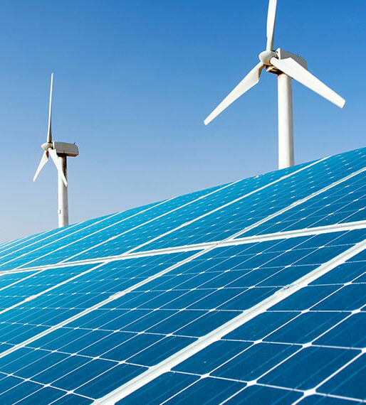 Großes Solarpanel vor Reihe weißer Windräder unter klarem blauem Himmel.