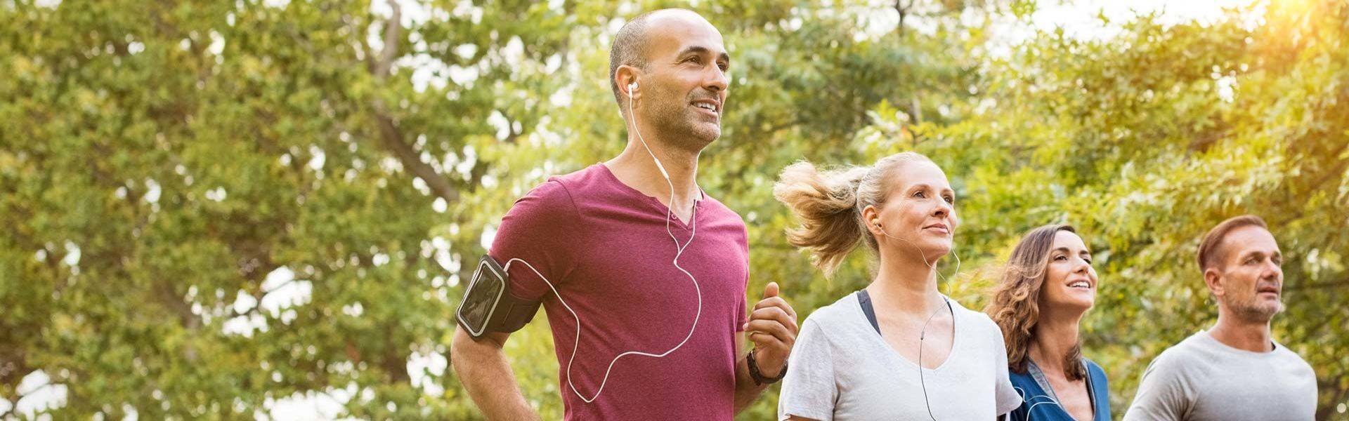 Zwei Frauen und zwei Männer joggen im Grünen