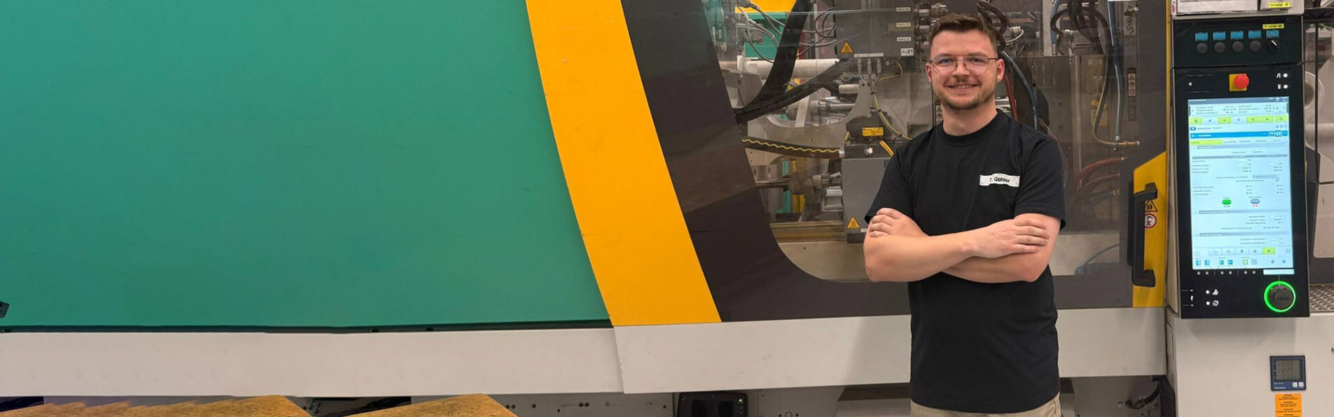 Eine Frau und ein Mann stehen vor einer geöffneten Lädesäule und lächeln sich an. Beide tragen eine Brille und der Mann hält einen Akkuschrauber in der Hand.