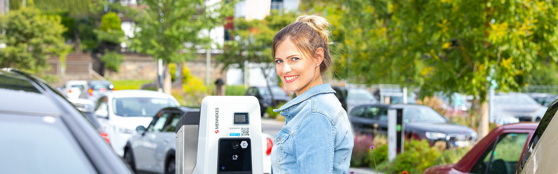 Kundin lädt ihr E-Auto auf Kundenparkplatz während des Einkaufens