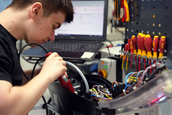 Ein Azubi zum Elektroniker für Betriebstechnik bei MENNEKES schraubt.