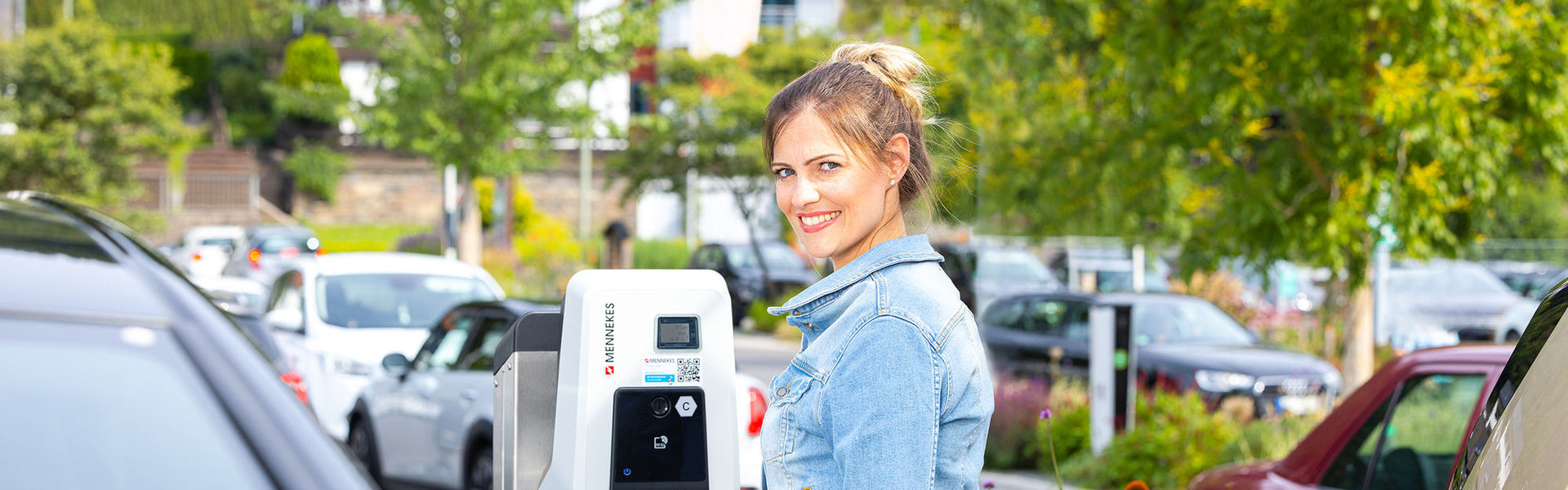 Kundin lädt ihr E-Auto auf Kundenparkplatz während des Einkaufens