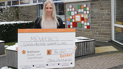 Eine Frau hält einen Spendenscheck in der Hand